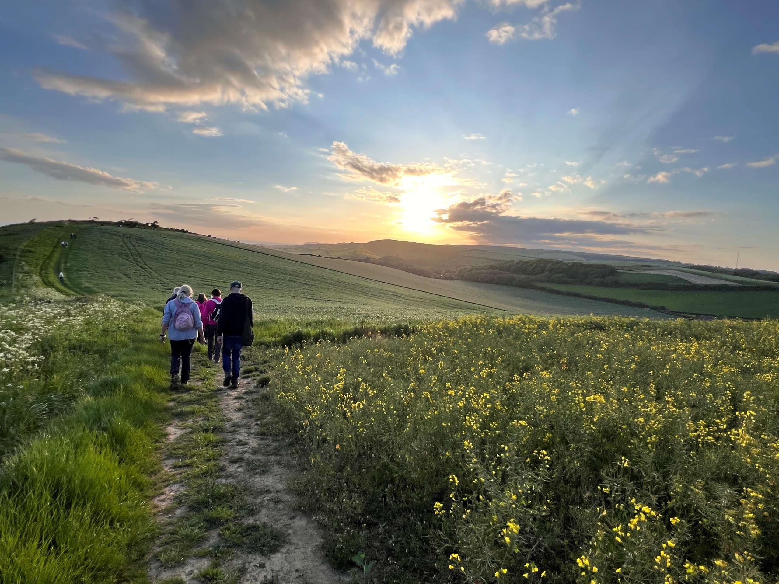 two people walking in the countryside wih the appearing from behind a cloud